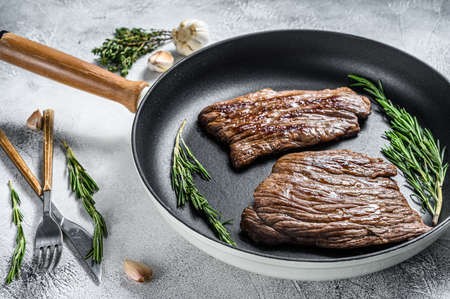 Grilled flat iron and flank steaks in a pan. Marble beef meat. Gray background. Top view.の写真素材