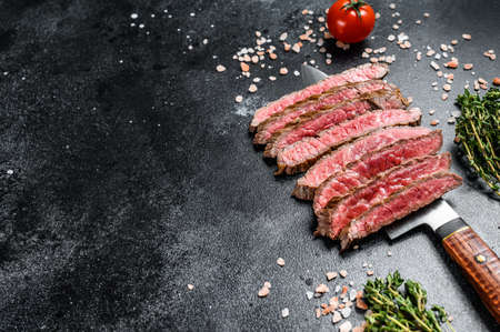 Grilled and sliced flat iron rare steak. Marble beef meat. Black background. Top view. Copy space.の写真素材