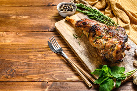 Roasted goat leg with herbs. Farm meat. Wooden background. Top view. Copy space.の写真素材