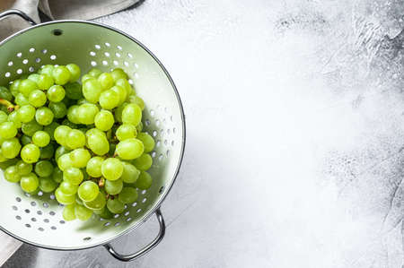 Green ripe grapes in a colander, fruits of autumn. White background. Top view. Copy space.の写真素材