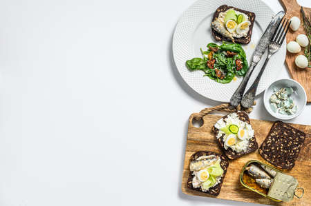 Sandwiches with sardines, egg, cucumber and cream cheese, salad garnish with spinach and dried...
