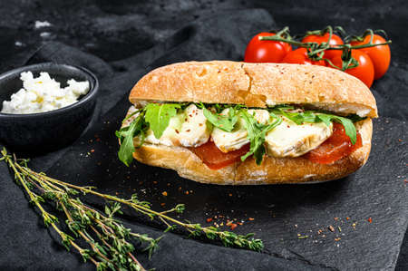 Ciabatta sandwich with fresh goat cheese, pear marmalade and arugula. Black background. Top view.の写真素材