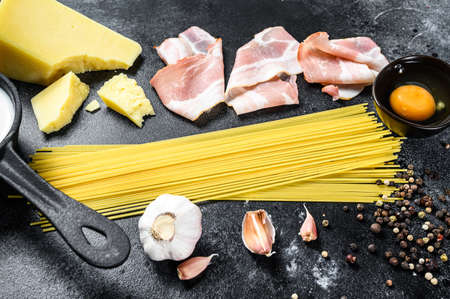 Traidtional Italian Pasta Carbonara Ingredients. Bacon, Spaghetti, Parmesan and pecorino cheese, egg, garlic. Black background. Top view.の写真素材