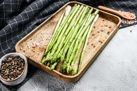 Fresh baby green asparagus in a wooden bowl. White background. Top view. Copy space.の写真素材