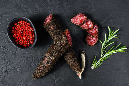 Fuet, Salami and a sprig of rosemary. Traditional Spanish sausage. Black background. Top view.の写真素材