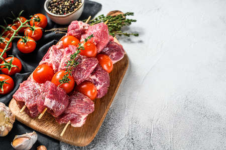 Raw fresh shish kebab. BBQ meat with tomato and spices. Gray background. Top view. Copy space.の写真素材