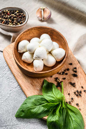 Mini mozzarella cheese in a wooden bowl with Basil leaves. gray background. Top view.の写真素材