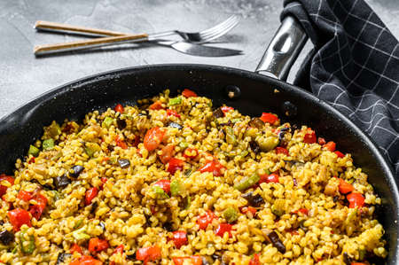 Cooked bulgur with vegetables and chicken meat in a pan. Gray background. Top view.の写真素材