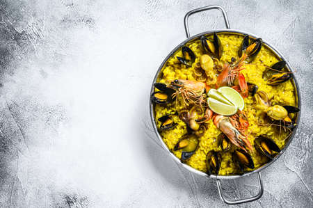 Seafood paella in the fry pan with prawns, shrimps, octopus and mussels. White background. Top view. Copy space.の写真素材