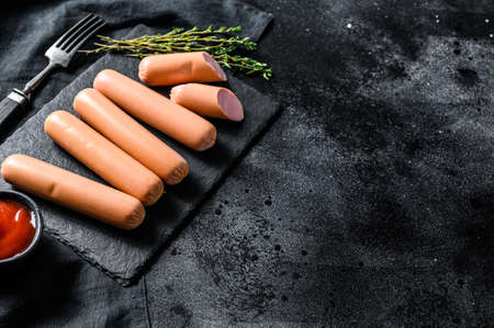 Raw pork classic sausages on a stone Board with rosemary and spices. Black background. Top view. Copy space.の写真素材