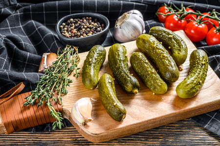 Marinated pickled cucumbers with herbs and spices on cutting board. Black background. Top view.の写真素材