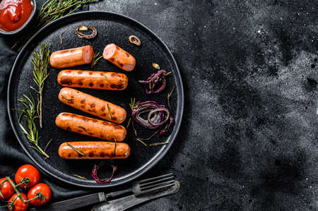 Grilled pork sausages with onion, garlic and rosemary. Black background. Top view. Copy space.の写真素材