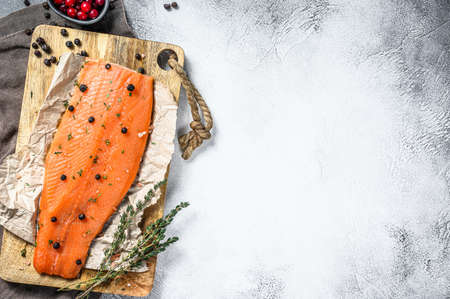 Cooking salted salmon fillet on a wooden cutting Board with herbs and spices. Gray background. Top view. Copy space.の写真素材