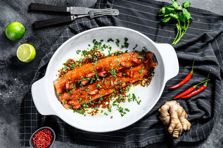 Cooking sea trout fillet teriyaki. Black background. Top view.