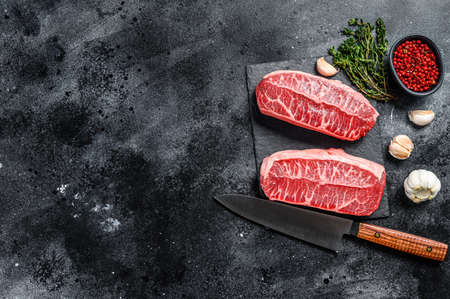 Raw top blade steak dry-aged on a stone board. Black background. Top view. Copy space.の写真素材