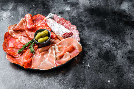 Cured meat platter of traditional Spanish tapas. Chorizo, jamon serrano, lomo and fuet. Black background. Top view. Copy space.の写真素材