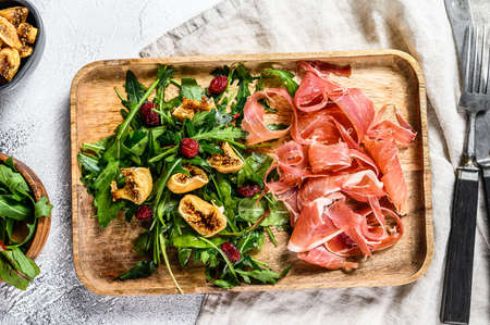 Salad with Serrano jamon, ham, rucola and fig. Antipasto. Gray background, top viewの写真素材