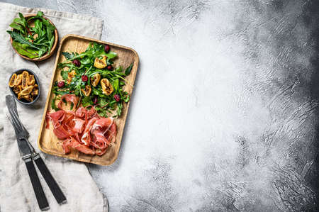 Salad with Parma, prosciutto ham, arugula and figs. Italian antipasti. Gray background, top view, space for text.の写真素材