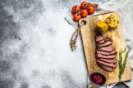 Sliced grilled filet Mignon steak on a wooden chopping Board. Beef tenderloin. Gray background. Top view. Space for textの写真素材