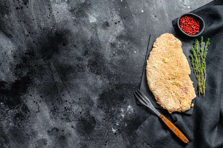 Raw Wiener Schnitzel, breaded steak ready to cook. Black background. Top view. Copy space.の写真素材