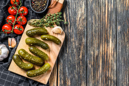 Marinated pickled cucumbers with herbs and spices on cutting board. Black background. Top view. Copy spaceの写真素材