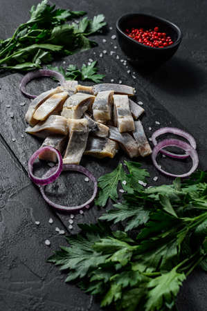 Marinated herring fillet with pepper, herbs and red onion. Black background. Top view.の写真素材