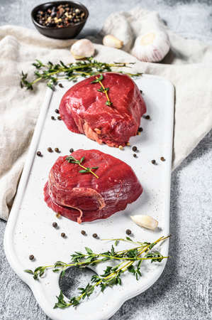 Marble beef tenderloin. Raw filet Mignon steak on a white chopping Board. Gray background. Top view.の写真素材