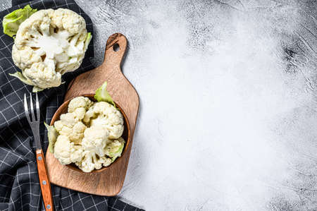 Raw cauliflower cut into pieces in wooden bowl. White background. Top view. Copy space.の写真素材