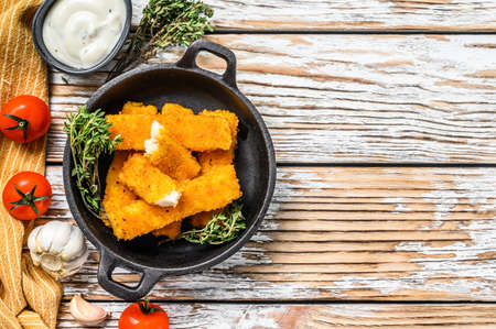 Crispy fish fingers with breadcrumbs served with sauce tartar in a pan. White background. Top view. Copy spaceの写真素材