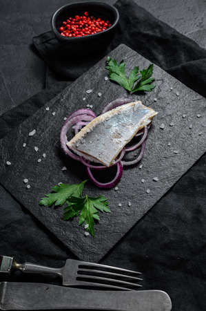 Traditional Dutch food herring with red onion. New season of herring called Hollandse nieuwe. Black background. Top view.の写真素材