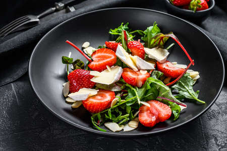 Brie cheese salad with strawberries, nuts, chard and arugula. Black background. Top view.の写真素材