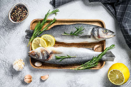 Raw sea bass fish with herbs and lemon. Black background. Top view.の写真素材
