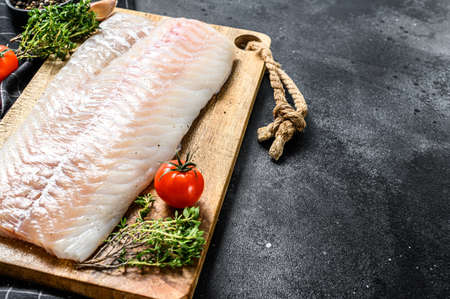 Fresh Raw Cod loin fillet with thyme. Black background. Top view. Copy space.