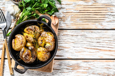 Rustic oven baked potatoes with rosemary. Organic vegetables. White background. Top view. Copy space.の写真素材