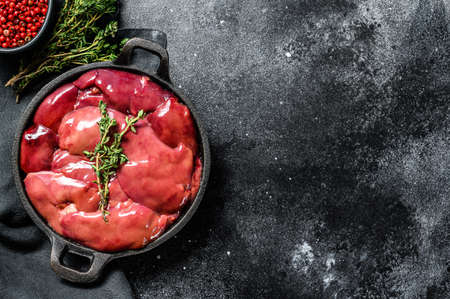 Raw Turkey liver in a frying pan. Black background. Top view. Copy space.の写真素材