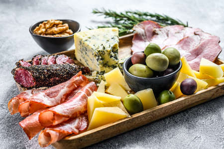 Italian appetizers or antipasto set mixed delicatessen of cheese and meat snacks. Gray background....