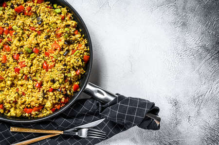 Cooked bulgur with vegetables and chicken meat in a pan. Gray background. Top view. Copy space