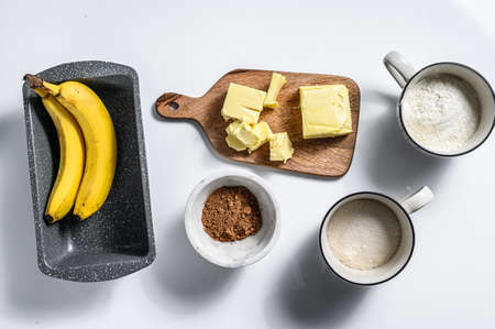 Ingredients for Banana bread recipe. Banana, chocolate, flour, egg, sugar, butter, chocolate. White background. Top view.の写真素材