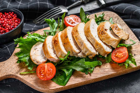 Fresh salad with grilled chicken breast, arugula and tomato. Black background. Top view.の写真素材