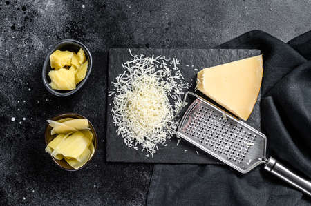 Pieces of parmigiano reggiano hard cheese. Slice, cut, grated. Black background. Top view.