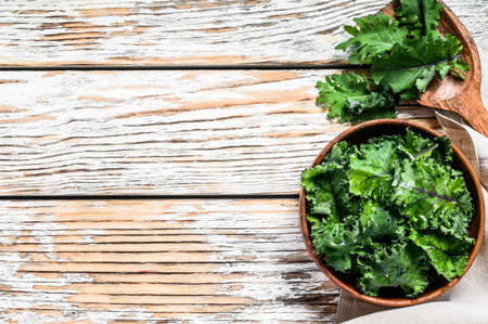 Fresh green superfood kale leaves in wooden bowl. Organic Vegetarian food. White background. Top view. Copy space.の写真素材