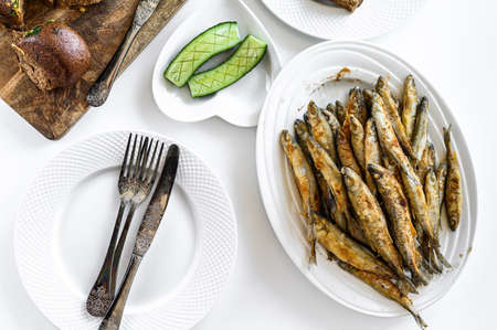 Appetizer of fried sprat and vegetables. White background. Top view.