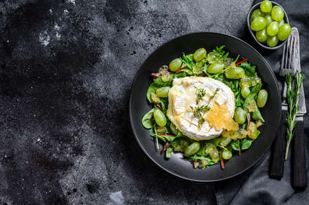 Salad with baked Camembert cheese, grapes, chard and arugula. Black background. Top view. Copy space.の写真素材
