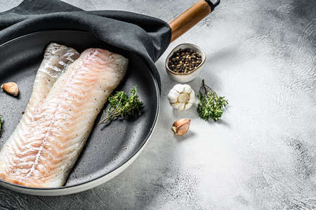 Raw cod loin with herbs in a frying pan. Gray background. Top view. Copy space.の写真素材
