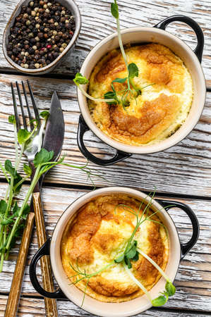 Cheese omelet with micro greens in a pan. White wooden background. Top view.の写真素材