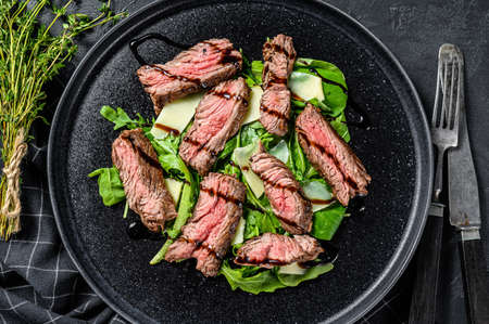 Steak salad with spinach, arugula and sliced beef marbled steak. Black background. Top view.の写真素材