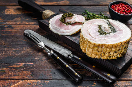 Pancetta, typical italian roll raw bacon. Dark Wooden background. Top view. Copy space.の写真素材