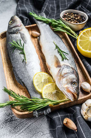 Raw sea bass fish with herbs and lemon. Black background. Top view.の写真素材