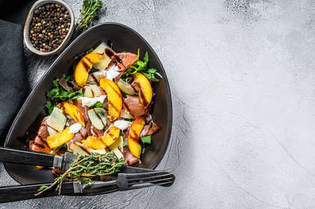 Salad with jamon Iberico, arugula, peach and Parmesan. Gray background. Top view. Copy space.の写真素材