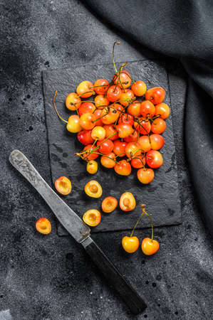 Yellow ripe cherries on a black plate. Black background. Top view.の写真素材